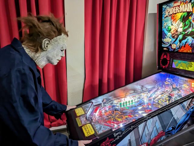 A player in a Halloween mask at a Spider-Man machine during a costumed league night
