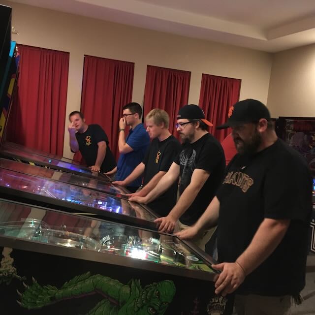 A group watching a game together, one player at the flippers